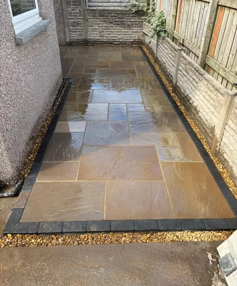 Natural stone paving finished with a dark border and gravel edging.